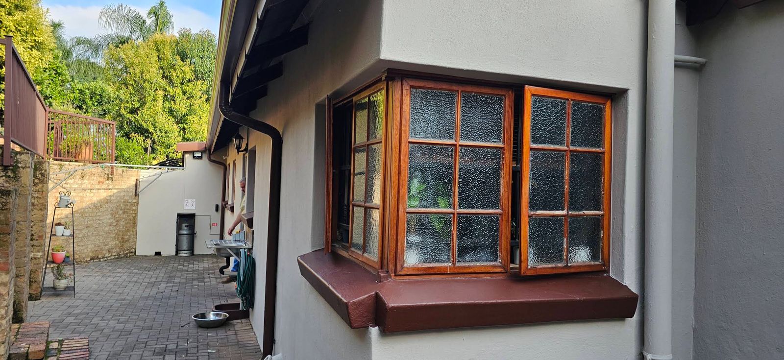 Freshly painted grey exterior with a varnished bay window and red-oxide sill