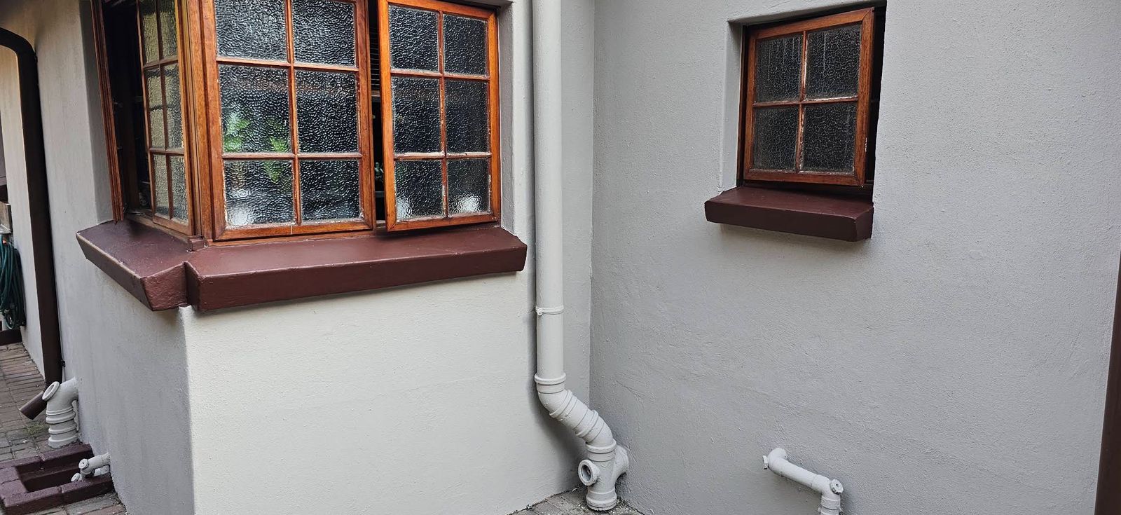 Red-oxide window sills, painted downpipes and grey walls
