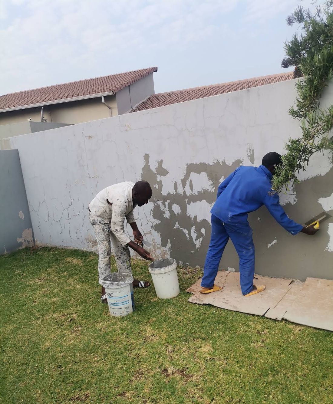 Two painters skimming a cracked wall